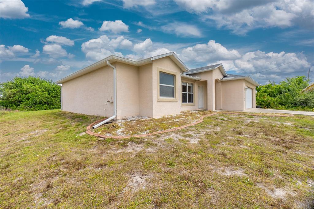 11708 Willmington Boulevard Port Charlotte, FL 33981 - Photo 40 of 41 a view of a white house next to a yard with large trees