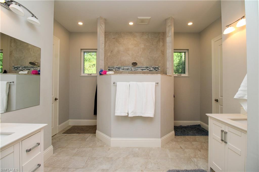 6184 Whitaker Road Naples, FL 34112 - Photo 13 of 50 a bathroom with a sink a mirror and a shower