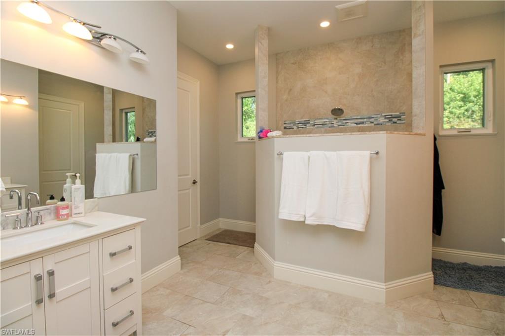 6184 Whitaker Road Naples, FL 34112 - Photo 14 of 50 a spacious bathroom with a shower sink and mirror