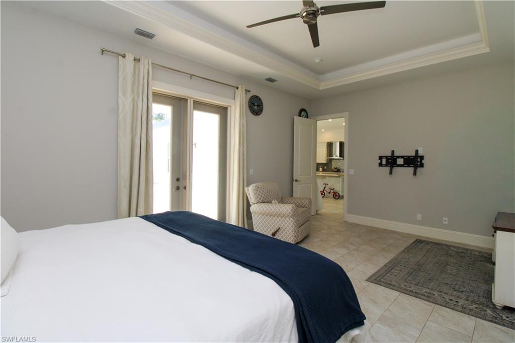6184 Whitaker Road Naples, FL 34112 - Photo 24 of 50 a bedroom with a large bed and a chandelier