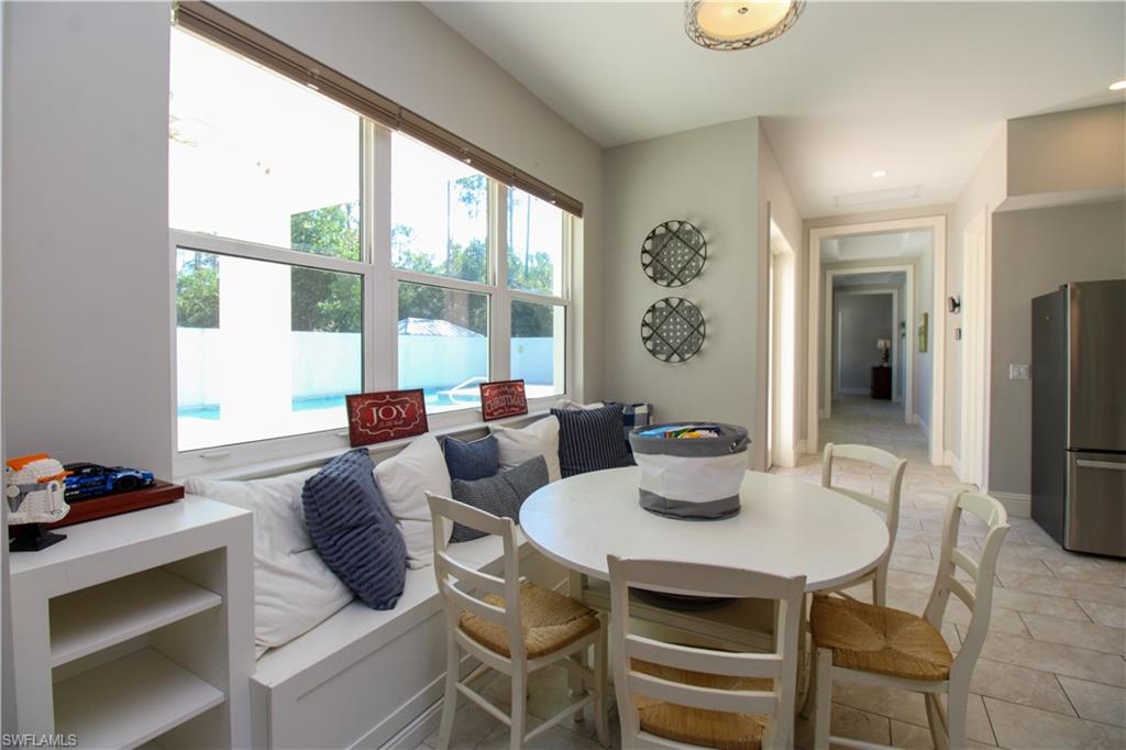 6184 Whitaker Road Naples, FL 34112 - Photo 32 of 50 a dining room with furniture a large window and a chandelier