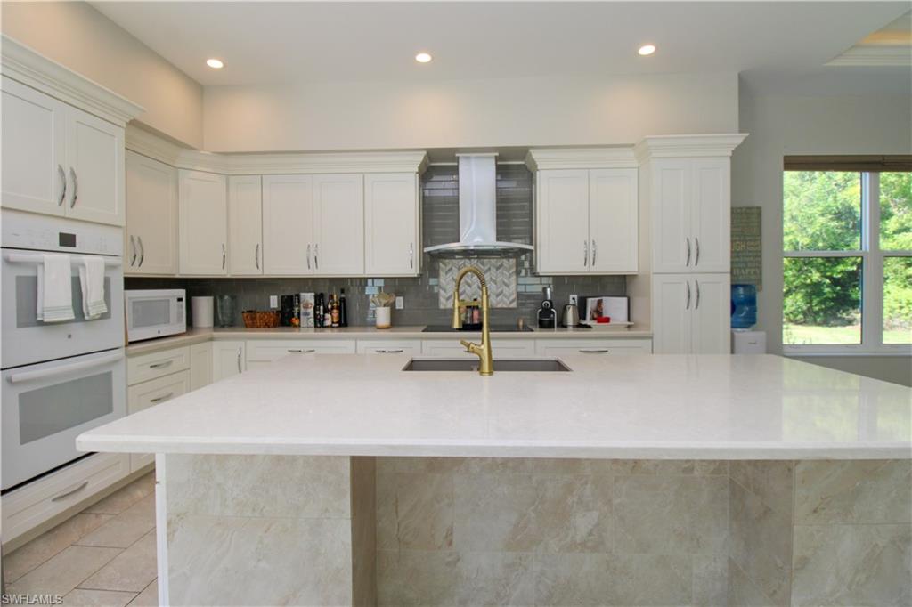 6184 Whitaker Road Naples, FL 34112 - Photo 34 of 50 a kitchen with stainless steel appliances granite countertop a sink a stove and a refrigerator with wooden floor