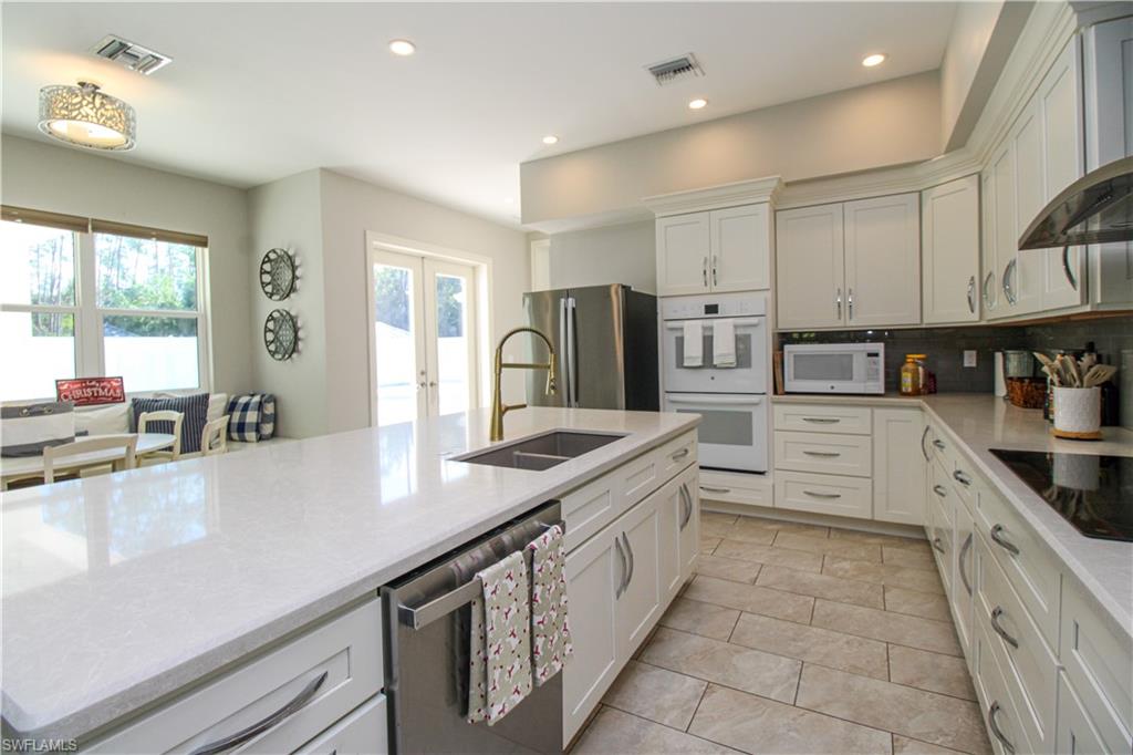 6184 Whitaker Road Naples, FL 34112 - Photo 37 of 50 a kitchen with stainless steel appliances granite countertop a sink counter space cabinets and a large window