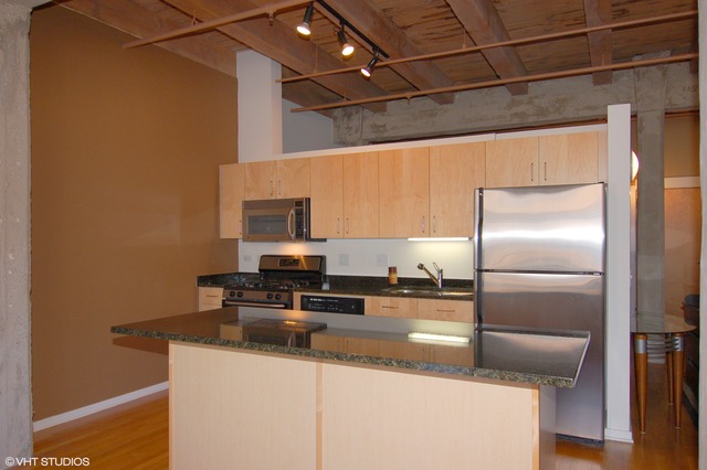 333 South Desplaines Street, Unit 605 Chicago, IL 60661 - Photo 5 of 8 a kitchen with kitchen island a counter top space cabinets stainless steel appliances and a counter top space