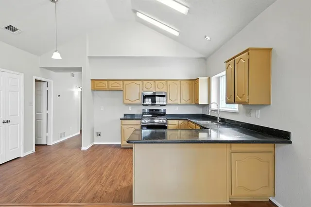 a kitchen with stainless steel appliances granite countertop a sink a stove counter space and cabinets