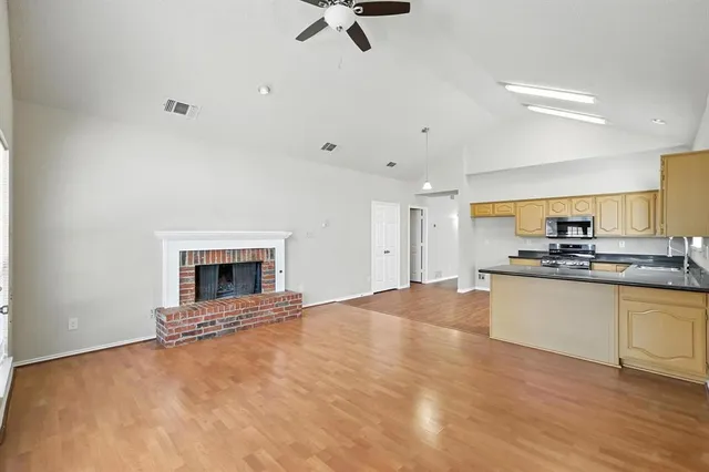 a view of open kitchen with sink wooden floor and a fireplace