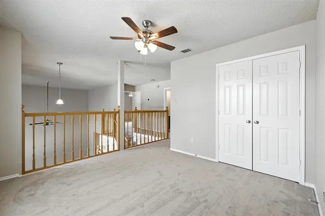 an empty room with ceiling fan and windows