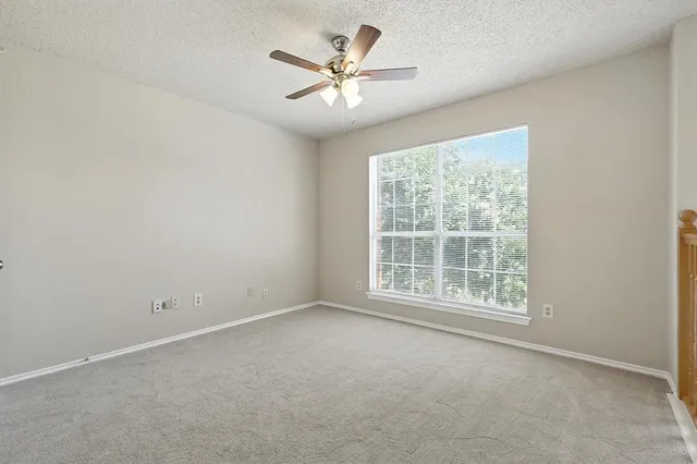an empty room with windows and ceiling fan