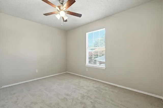 an empty room with a window and a fan
