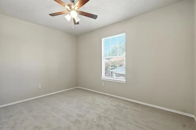 an empty room with a window and a fan