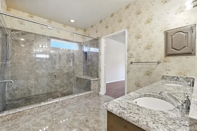 a bathroom with a granite countertop shower a sink and a mirror