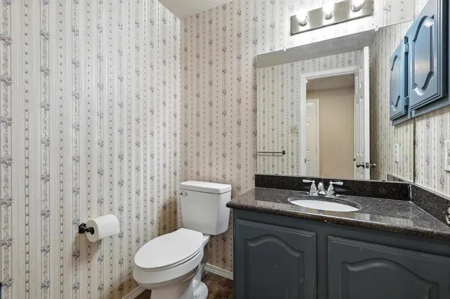 a bathroom with a granite countertop toilet a sink and a mirror