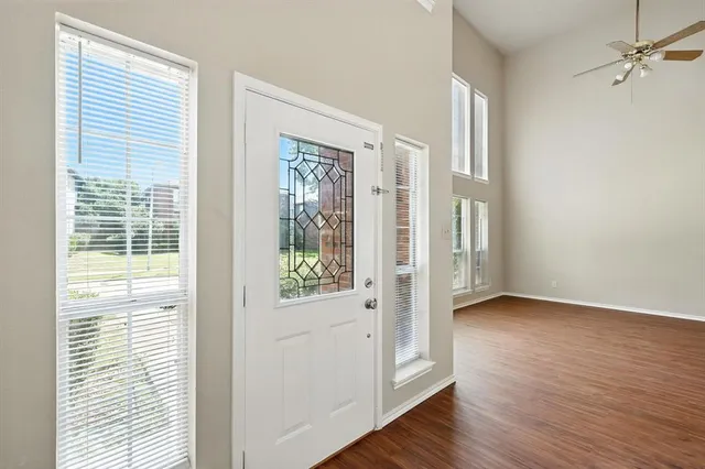 a view of an empty room with a window and wooden floor