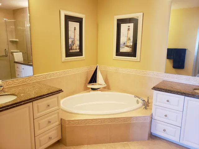a bathroom with a granite countertop sink a tub and a mirror