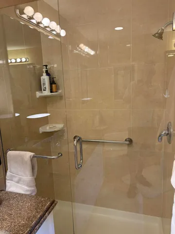 a bathroom with a granite countertop sink a mirror and shower