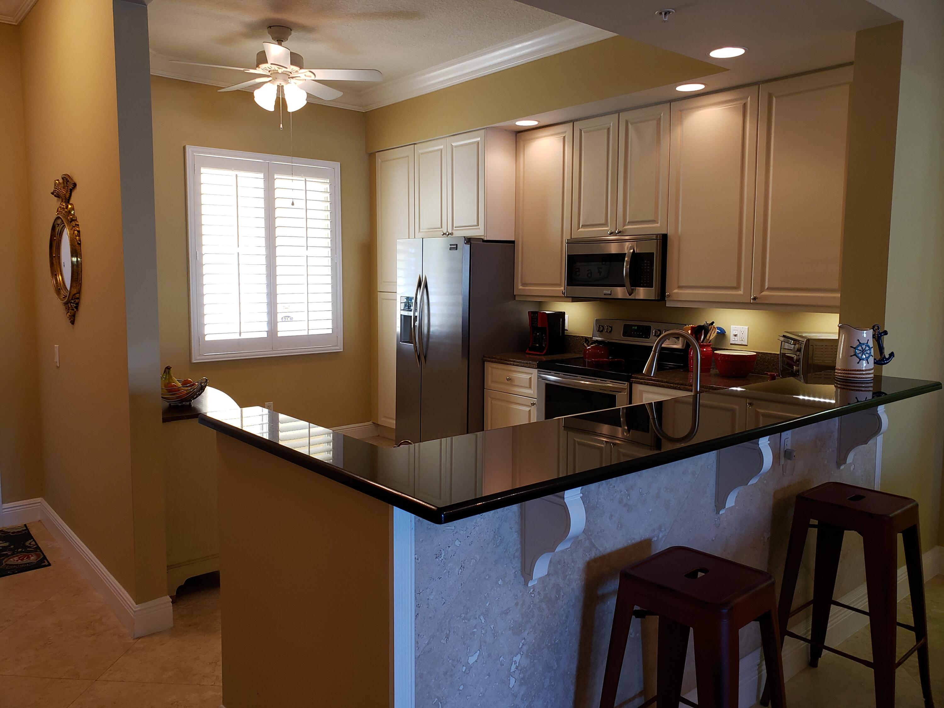 14 Harbour Isle Drive West, Unit 106 Fort Pierce, FL 34949 - Photo 6 of 23 a kitchen with kitchen island granite countertop a sink cabinets and stainless steel appliances