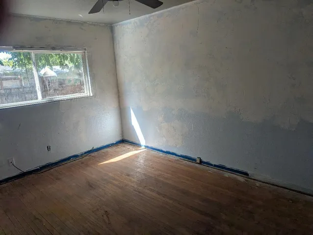 an empty room with wooden floor and windows