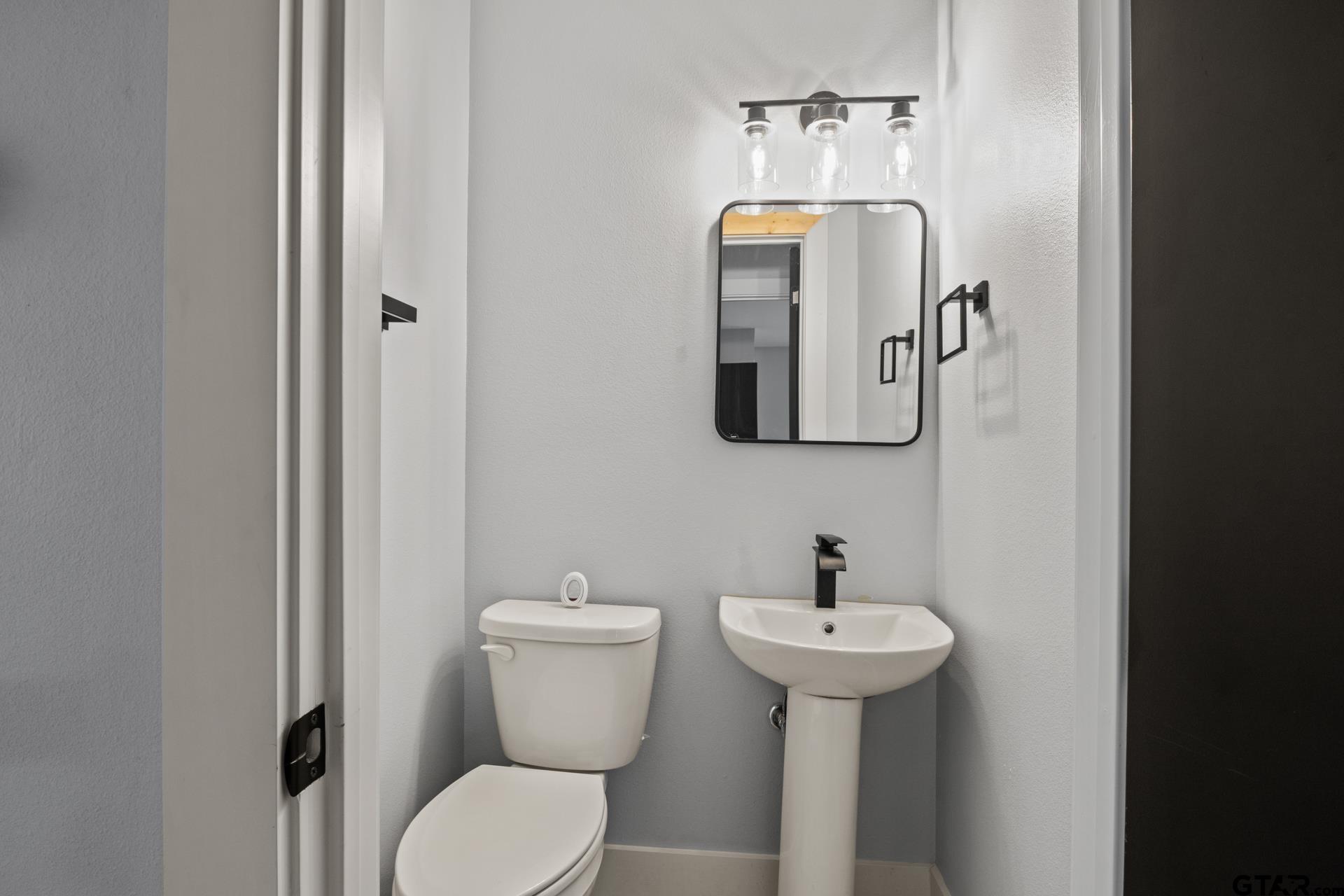 802 Quitman Street Pittsburg, TX 75686 - Photo 21 of 24 a bathroom with a toilet sink and mirror