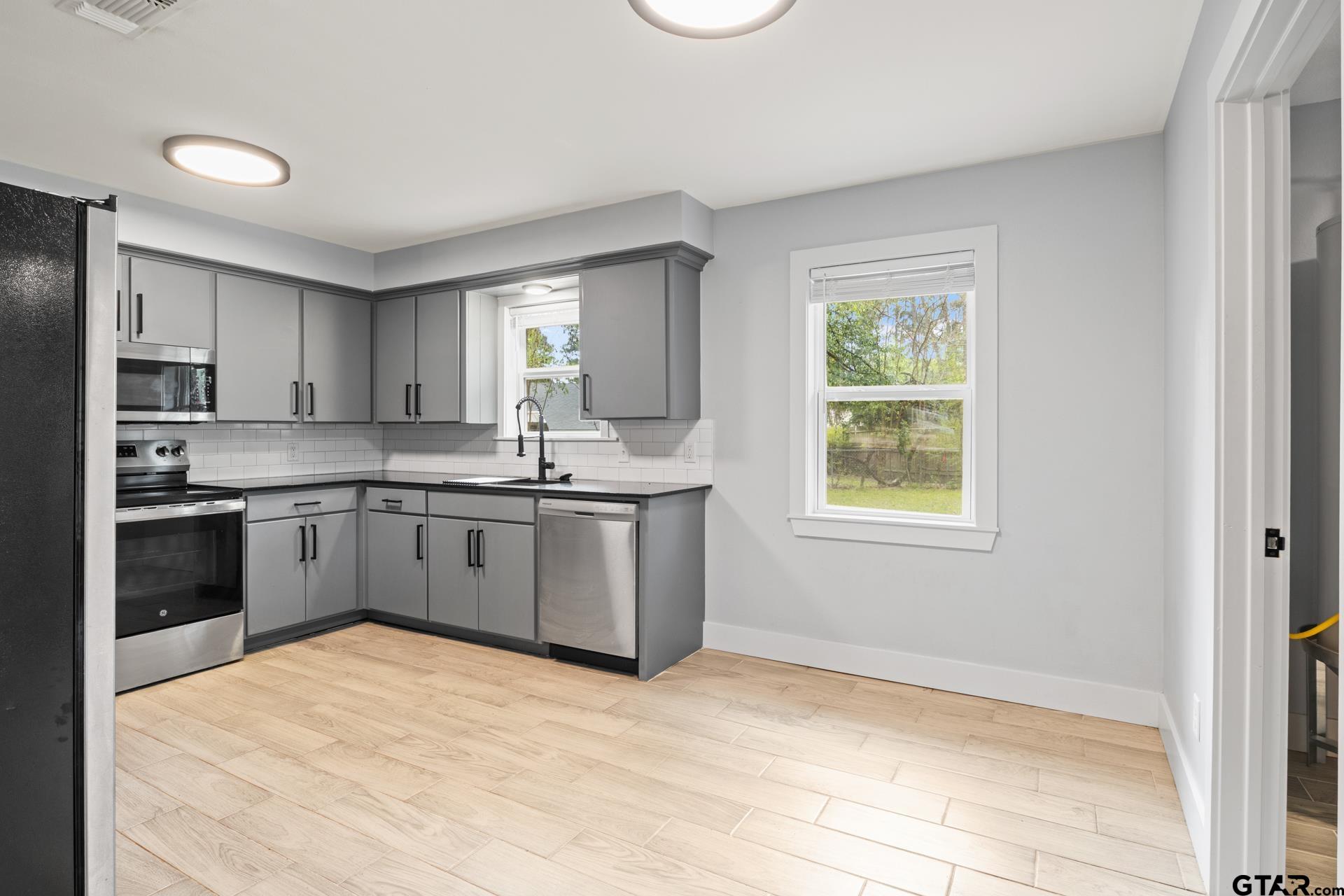 802 Quitman Street Pittsburg, TX 75686 - Photo 8 of 24 a kitchen with a stove a sink dishwasher a refrigerator and cabinets