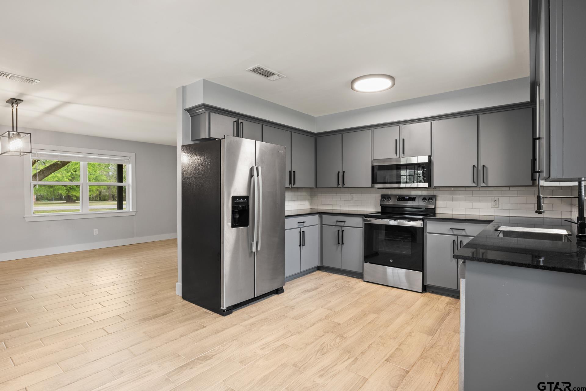 802 Quitman Street Pittsburg, TX 75686 - Photo 9 of 24 a kitchen with stainless steel appliances a refrigerator stove microwave and sink