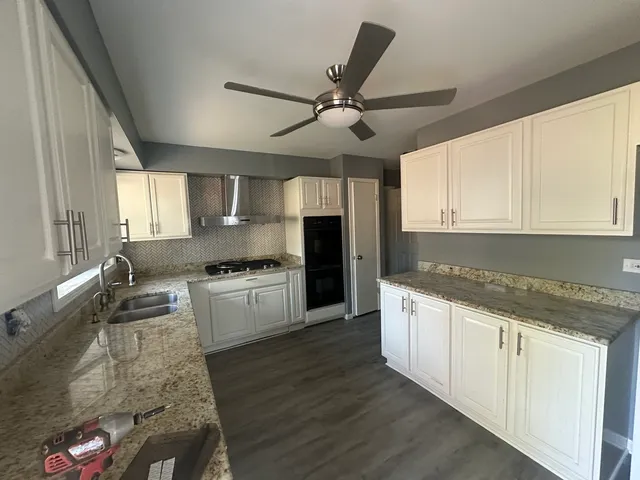 a large kitchen with granite countertop a stove sink and cabinets