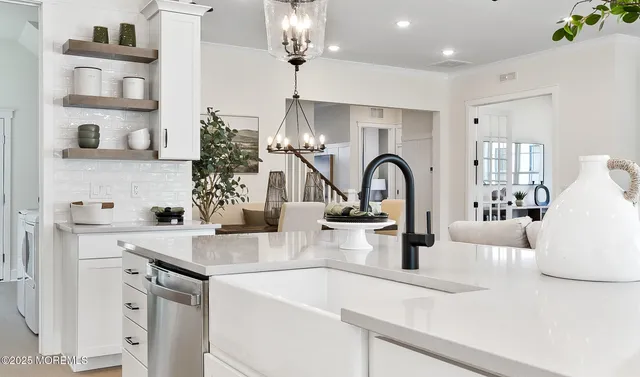 a kitchen with a sink dishwasher a stove and a dining table with wooden floor