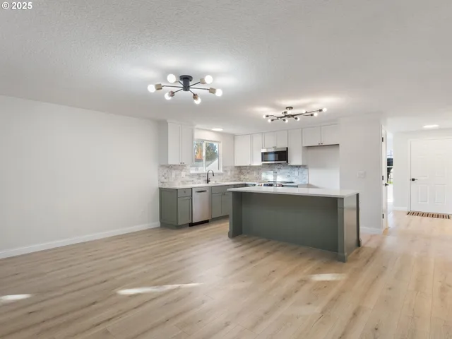 an empty room with wooden floor chandelier fan and windows