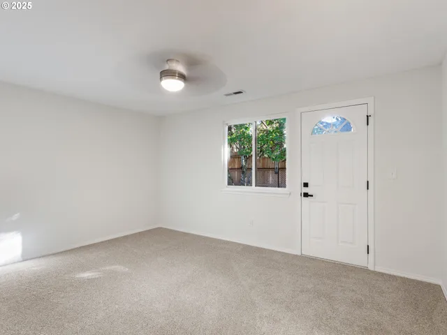 a view of an empty room and a chandelier fan