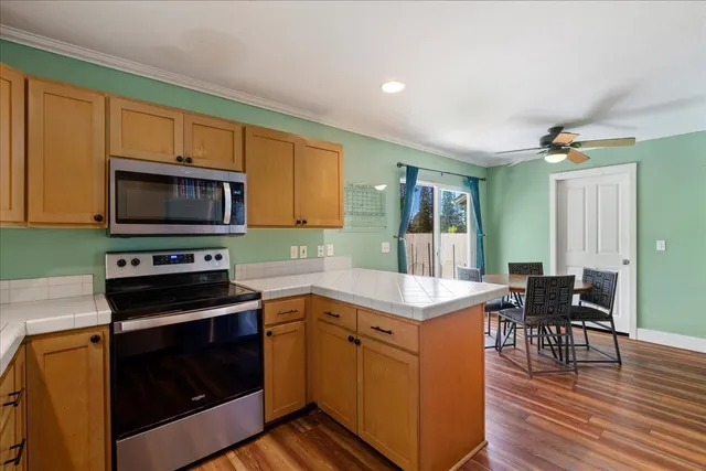 a kitchen with granite countertop a stove a sink a dining table and chairs with wooden floor