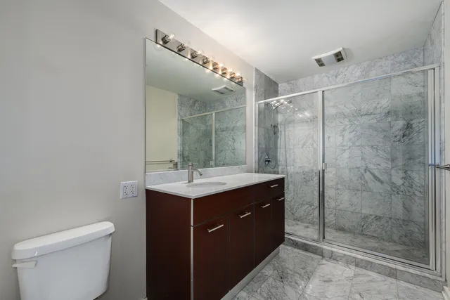 a bathroom with a shower sink vanity and toilet