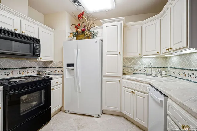 a kitchen with granite countertop white cabinets stainless steel appliances and sink