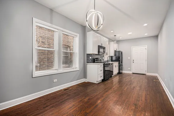 a view of kitchen with granite countertop stainless steel appliances cabinets a window and a chandelier