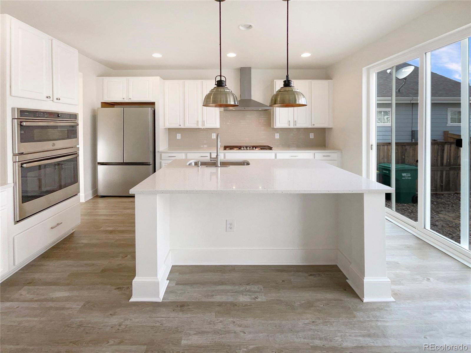 27895 East 7th Place Aurora, CO 80018 - Photo 14 of 35 a large kitchen with kitchen island a stove a refrigerator a sink and a fireplace