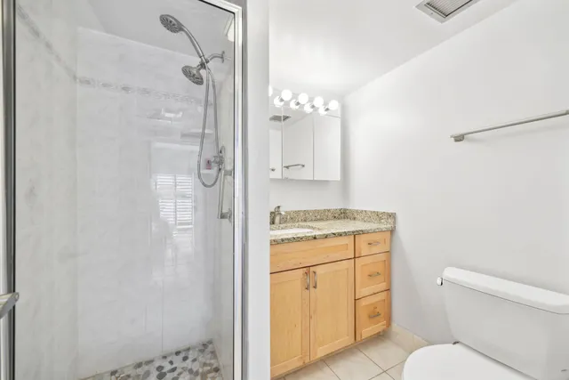a bathroom with a granite countertop sink toilet and shower