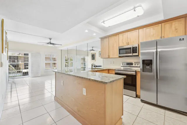 a kitchen with stainless steel appliances granite countertop a refrigerator a sink a stove top oven and cabinets