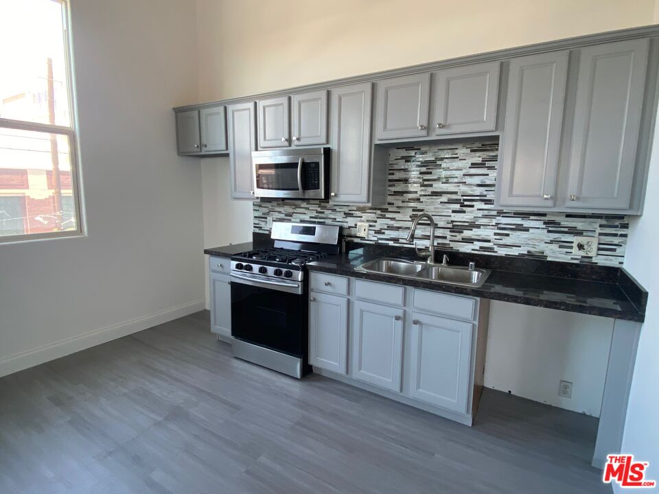 726 South Santa Fe Avenue, Unit 303 Los Angeles, CA 90021 - Photo 6 of 8 a kitchen with stainless steel appliances granite countertop a stove a sink and a microwave