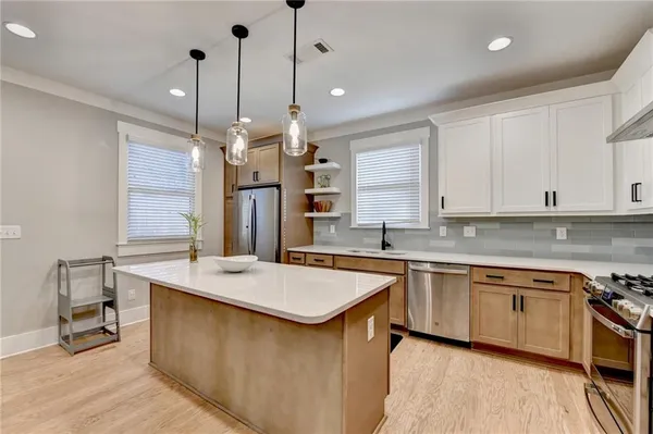 a kitchen with stainless steel appliances a refrigerator a sink a stove a center island and cabinets