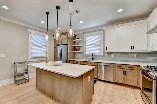 a kitchen with stainless steel appliances a refrigerator a sink a stove a center island and cabinets