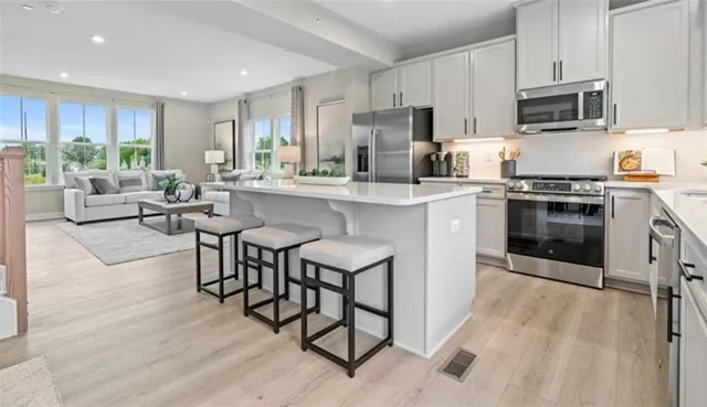 a kitchen with stainless steel appliances granite countertop a stove top oven a sink dishwasher a dining table and chairs with wooden floor