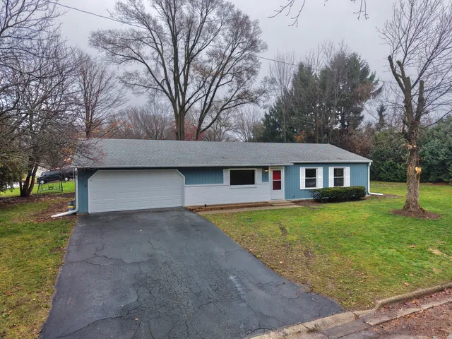 a front view of a house with yard garden and trees