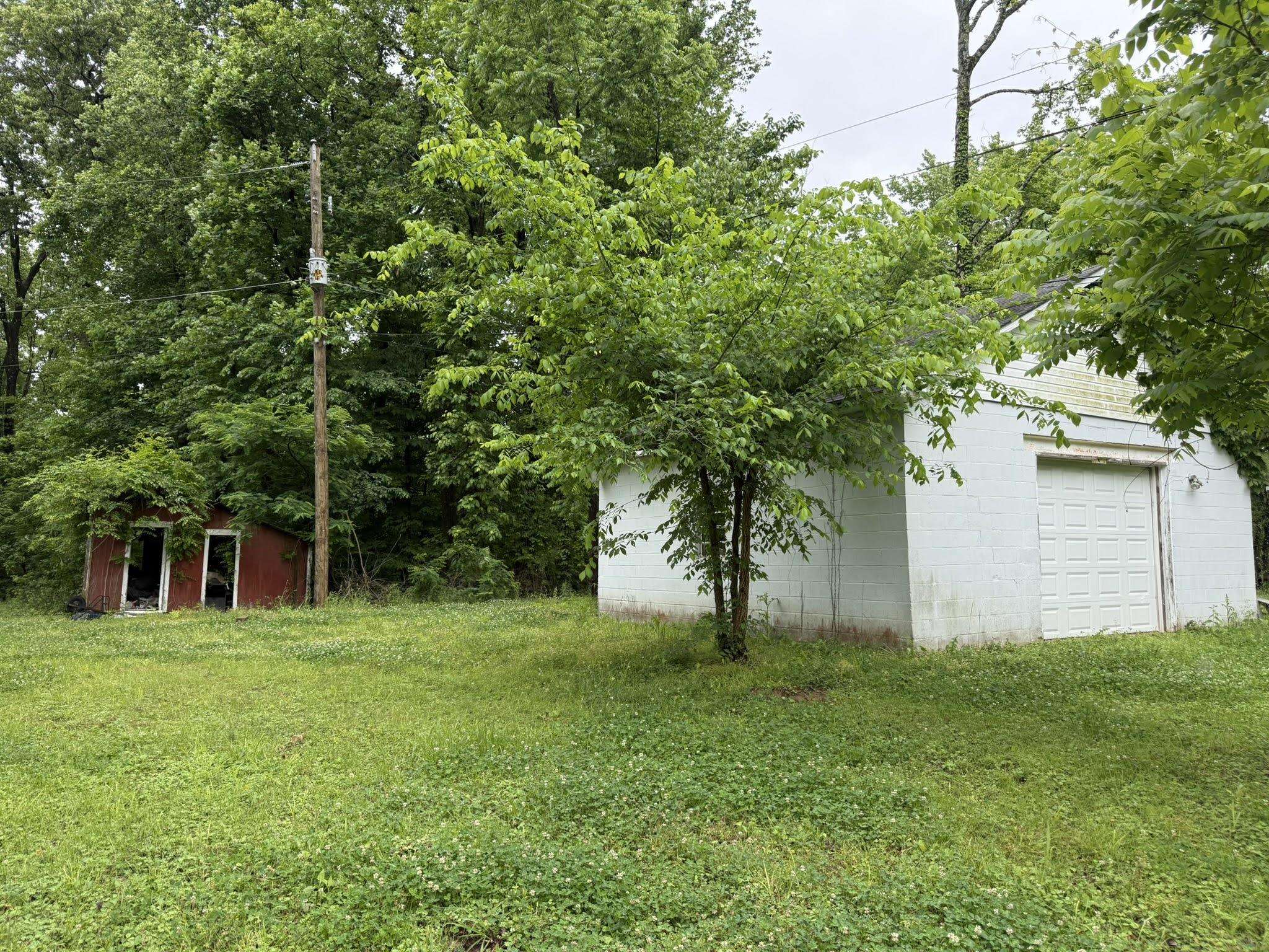 1299 Locke Cuba Road Millington, TN 38053 - Photo 26 of 28 White block structure with a paneled garage door and a separate red storage shed