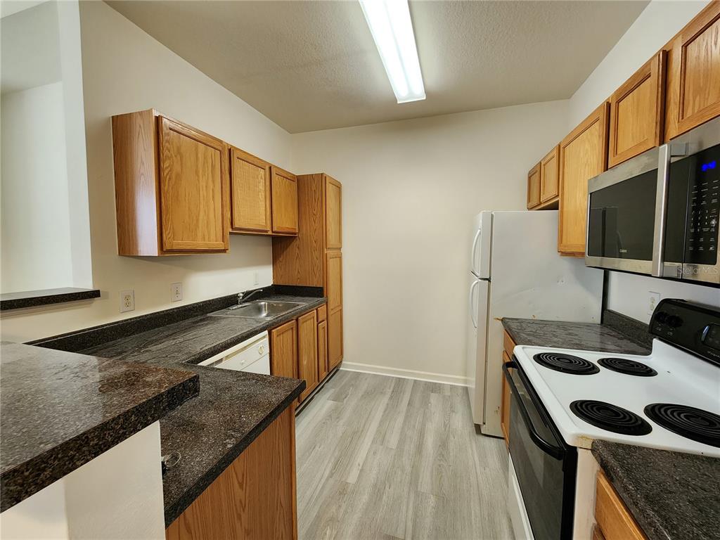 4802 51st Street West, Unit 1418 Bradenton, FL 34210 - Photo 3 of 20 a kitchen with a sink a stove and a microwave