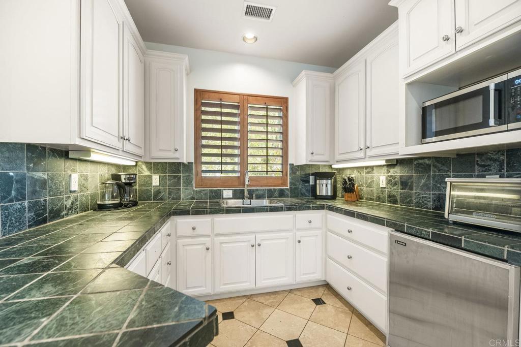 15615 Boulder Ridge Lane Poway, CA 92064 - Photo 48 of 75 a kitchen with white cabinets appliances a sink and a window