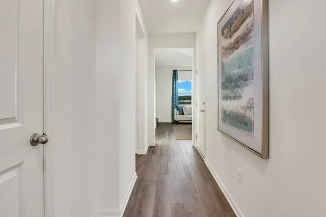 a view of a hallway with wooden floor and a bathroom