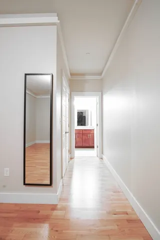 a view of a hallway with wooden floor and a bathroom