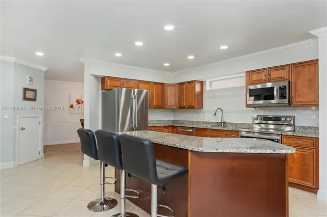 a kitchen with stainless steel appliances granite countertop a sink a stove a refrigerator cabinets and chairs
