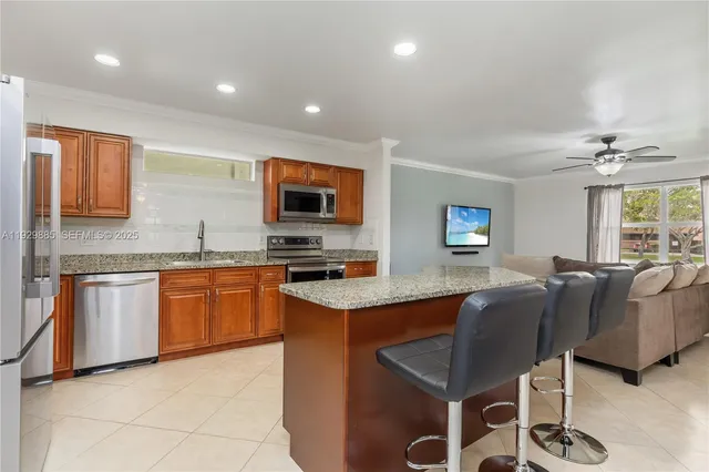 a kitchen with stainless steel appliances granite countertop a refrigerator oven a sink a dining table and chairs with wooden floor