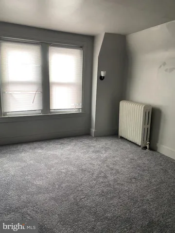 a view of an empty room with wooden floor and stairs
