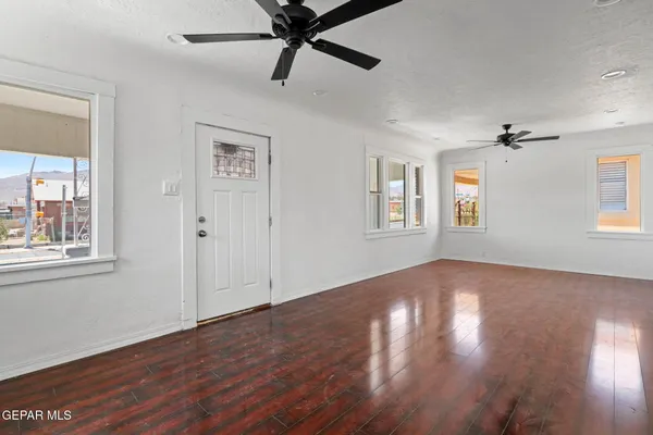 a view of empty room with wooden floor and fan