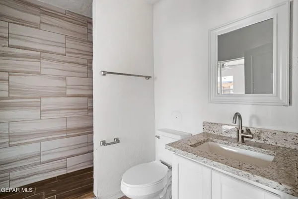 a bathroom with a granite countertop toilet sink and mirror